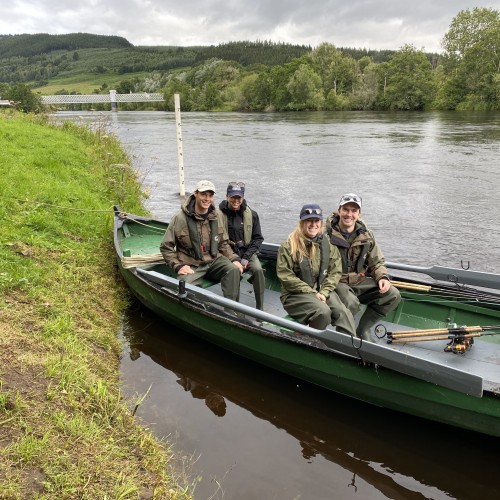 Here's 2 young couples ready in the boat to be taken down river to the superb salmon fishing locations near the River Tummel mouth area. You can see the hand carved black painted digits on the while plastic lumber water gauge behind the boat and the old grey painted iron railway bridge at Logierait in the distance.